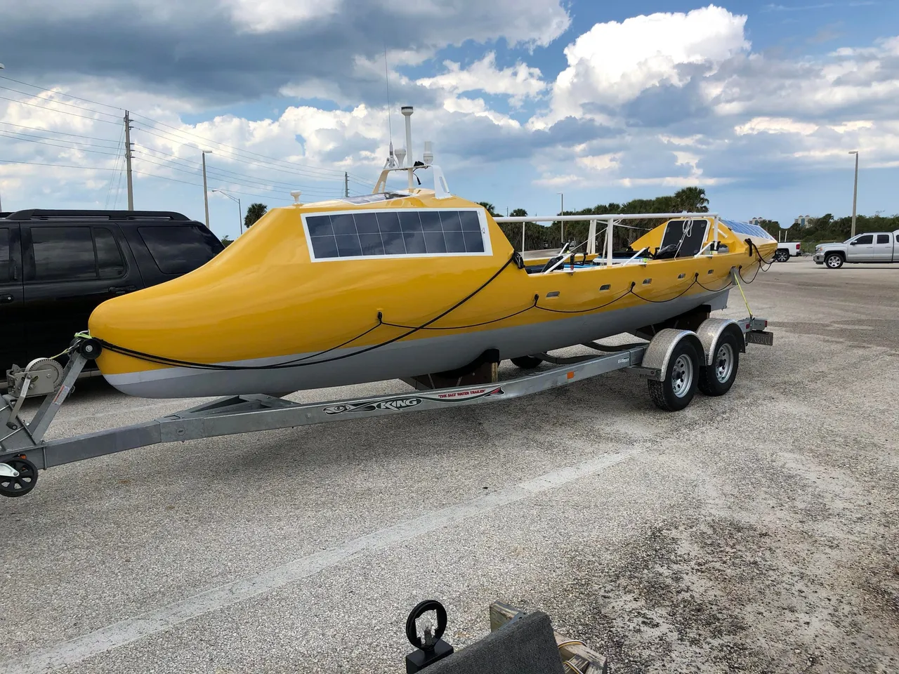 Yellow ocean-rowing boat on its trailer, showing the cabins and solar panels